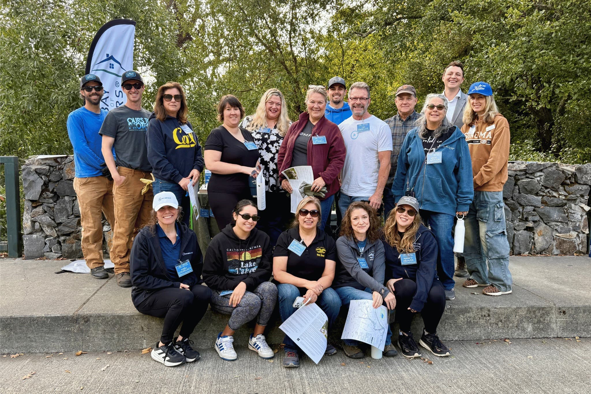 NORBAR members in volunteer shirts and name badges posed together on a creekside path at a community workday