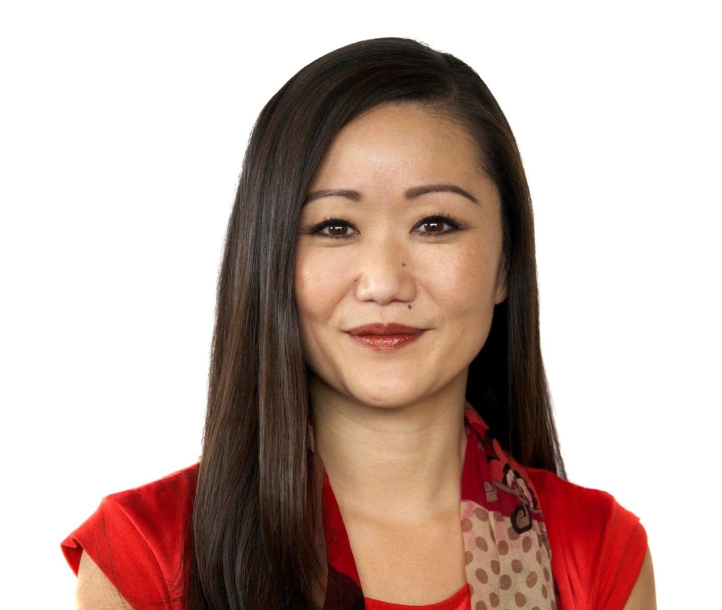 Studio headshot of a smiling woman with long dark hair in a red top, accompanying the Government Affairs Director's column.
