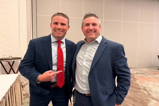 Two NORBAR members in navy suits smiling together at CAR Legislative Day in Sacramento.