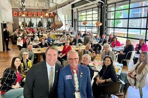 Large group of REALTORS gathered at long tables in a cafeteria hall during the CAR Legislative Day trip.