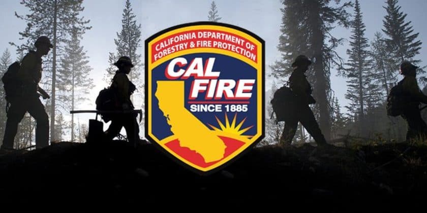 CAL FIRE shield logo over a photo of firefighters silhouetted on a fire line in smoky forest.
