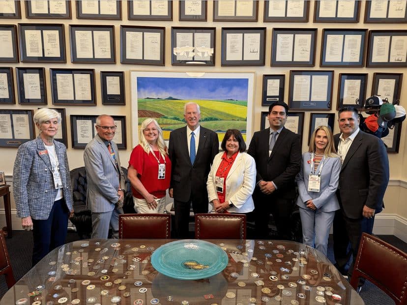REALTOR delegation posed with a member of Congress in a Capitol Hill office lined with framed documents.