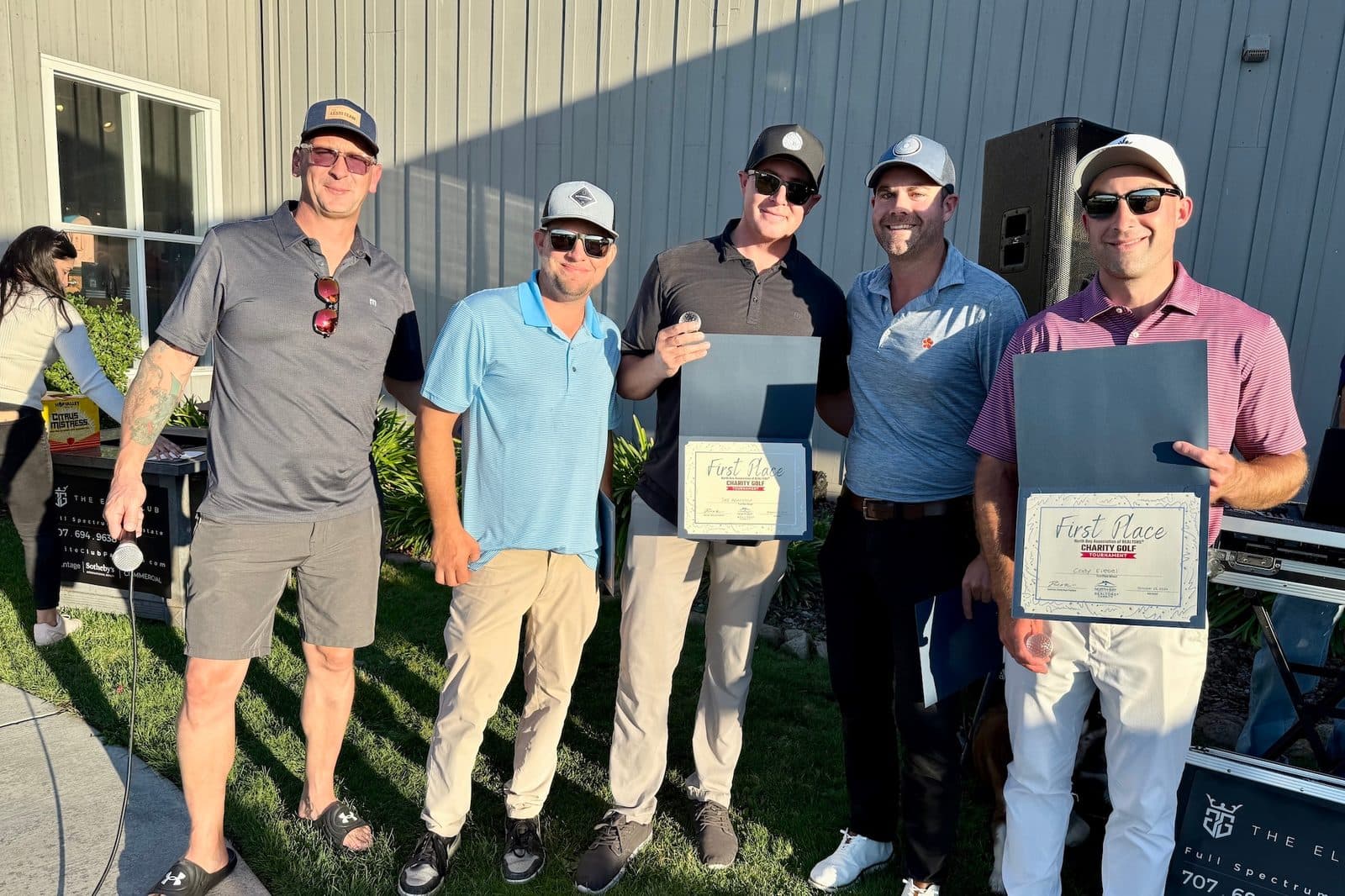 Five golfers holding First Place certificates from the NORBAR Charity Golf Tournament at the course.
