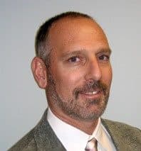 Neil Kalin, a bearded man in a tweed jacket and tie, against a pale green background.